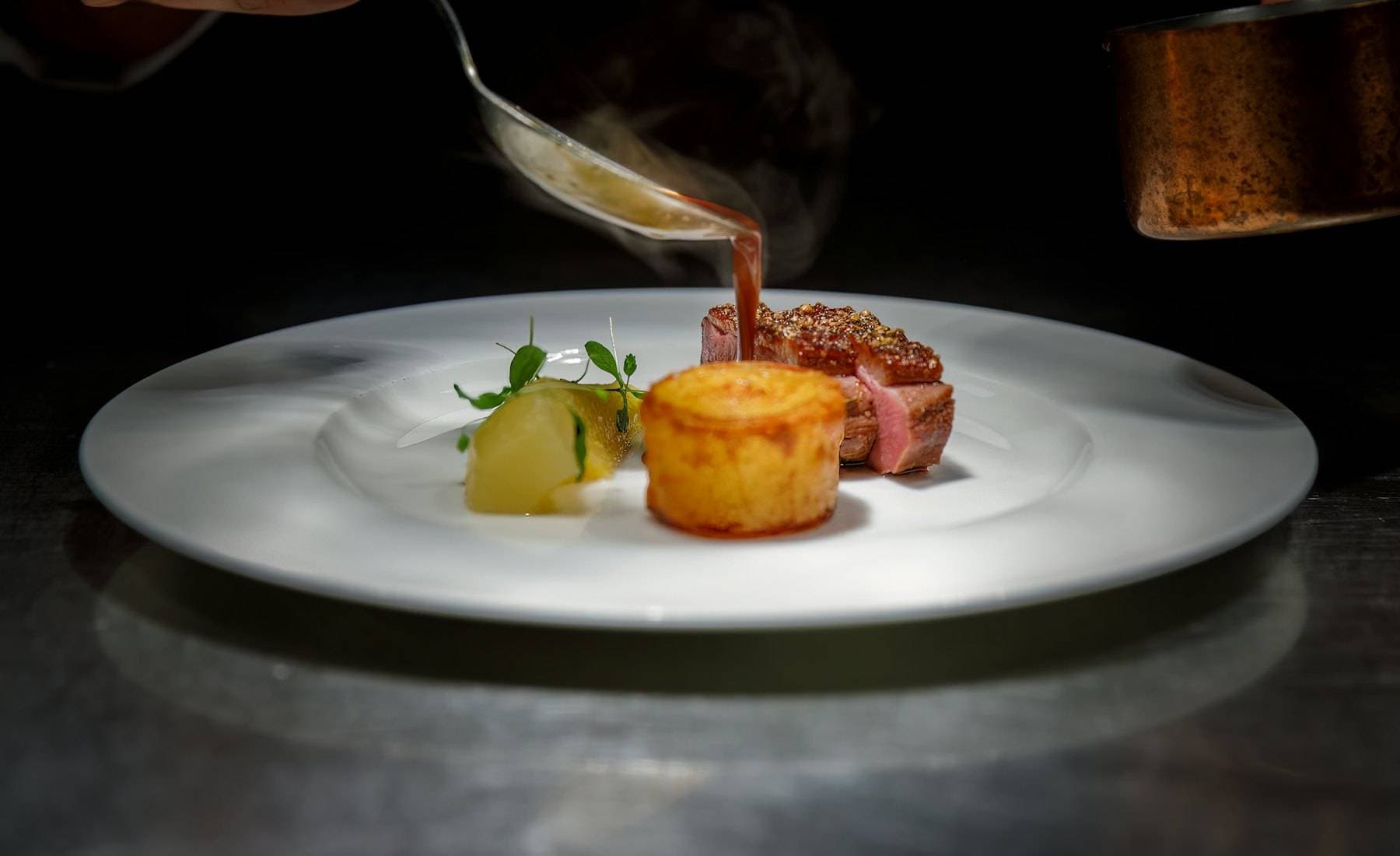 Chef pouring sauce over a plated dish